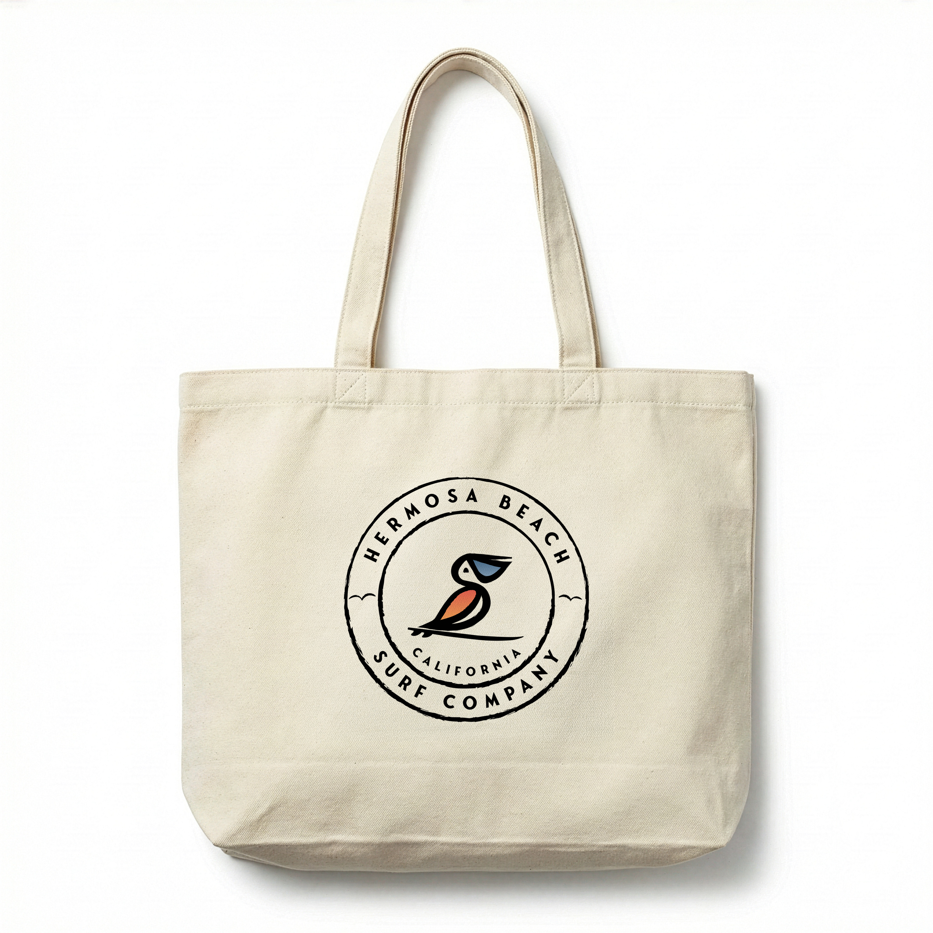 Beige tote bag with Hermosa Beach Surf Company logo on a white background
