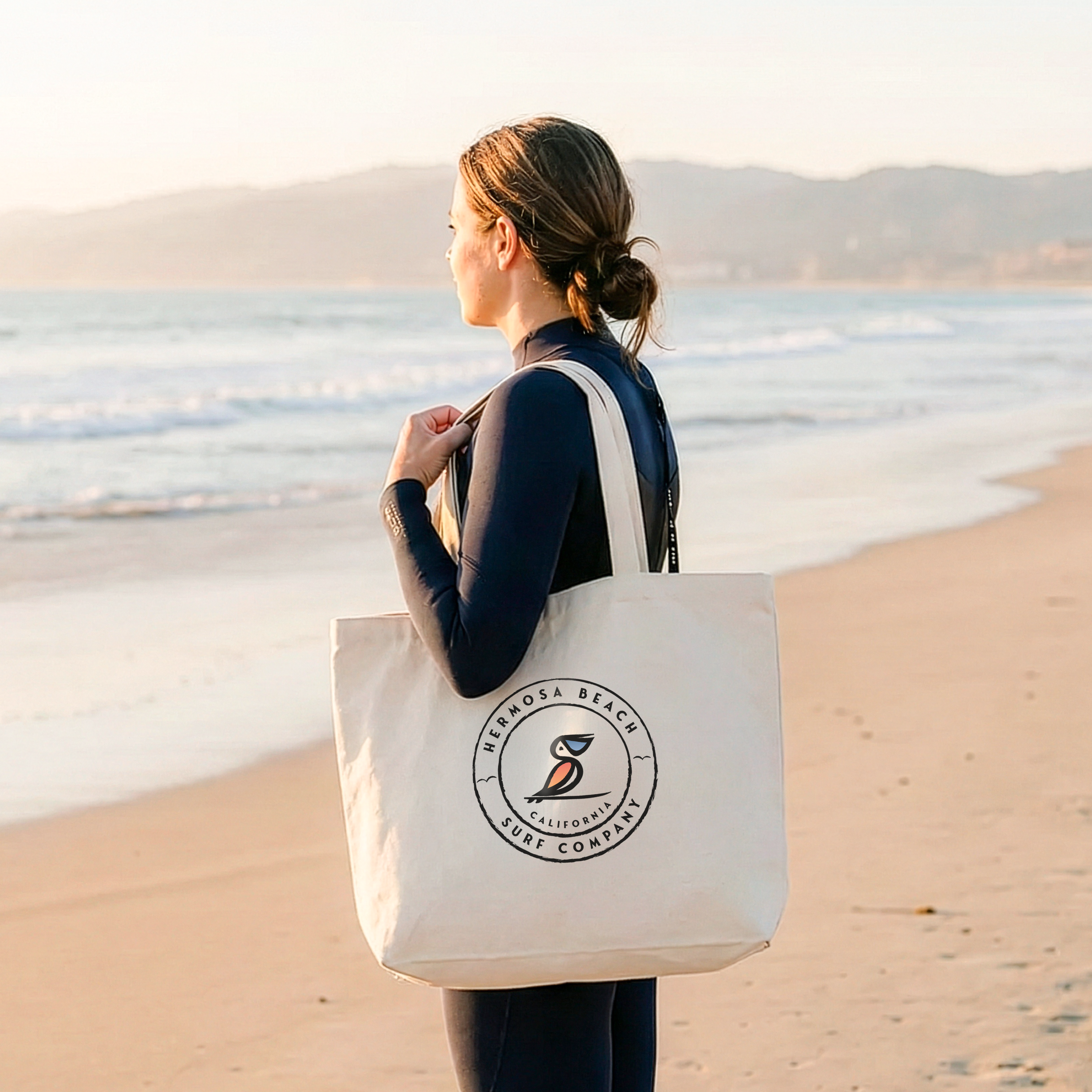 Person holding a tote bag with a logo on a beach
