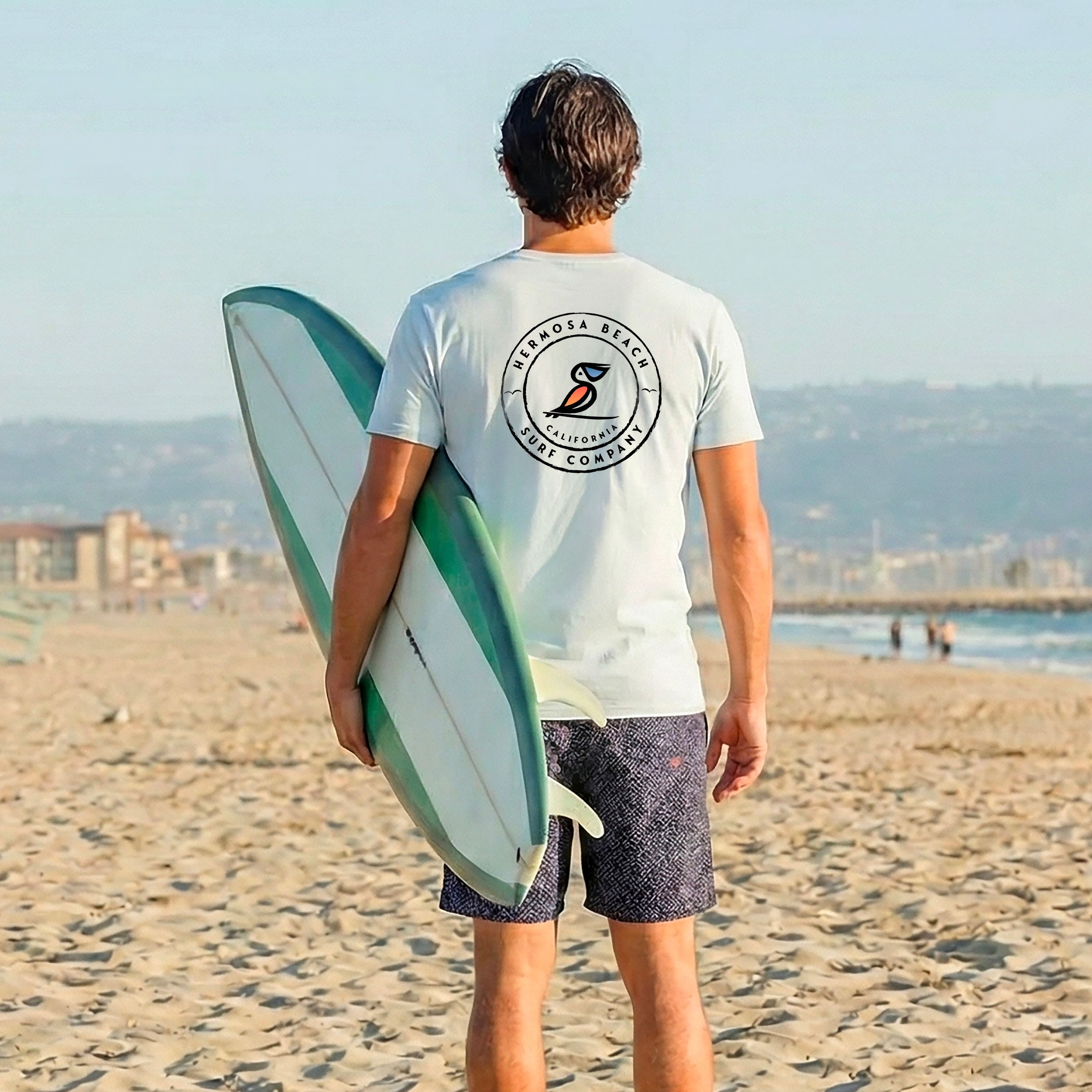 Person holding a surfboard on a beach with a clear sky