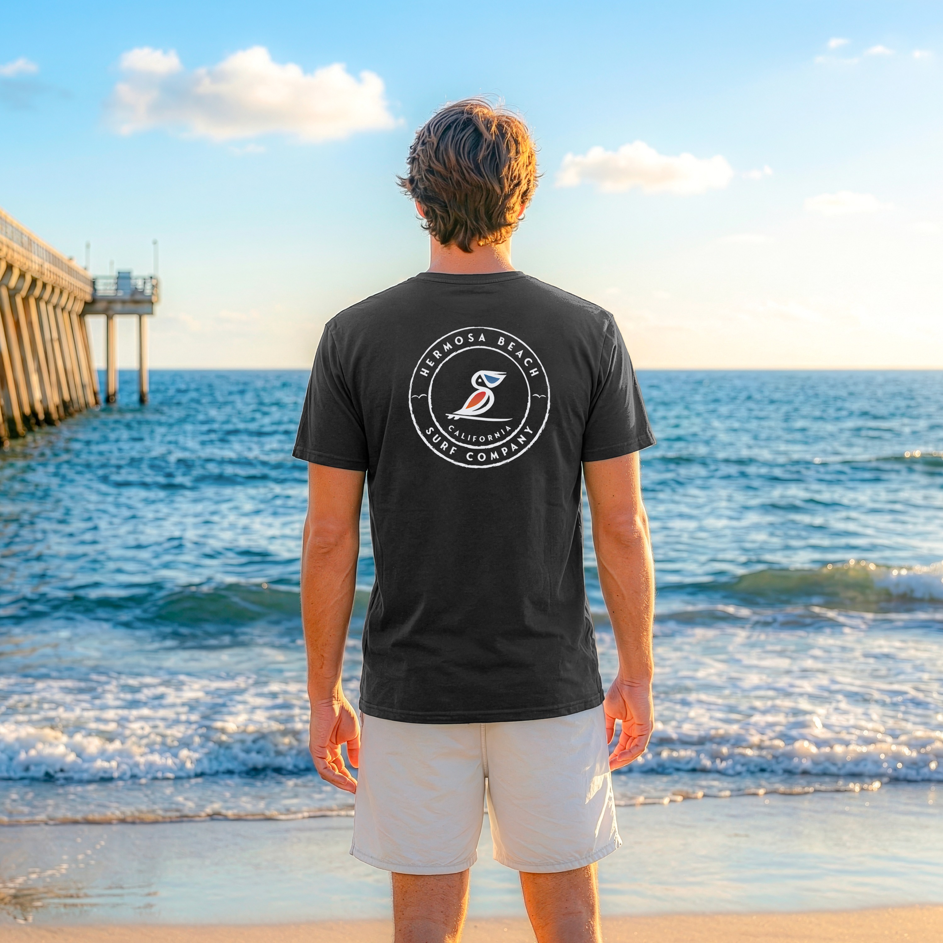 Man wearing a black t-shirt with a logo on the beach