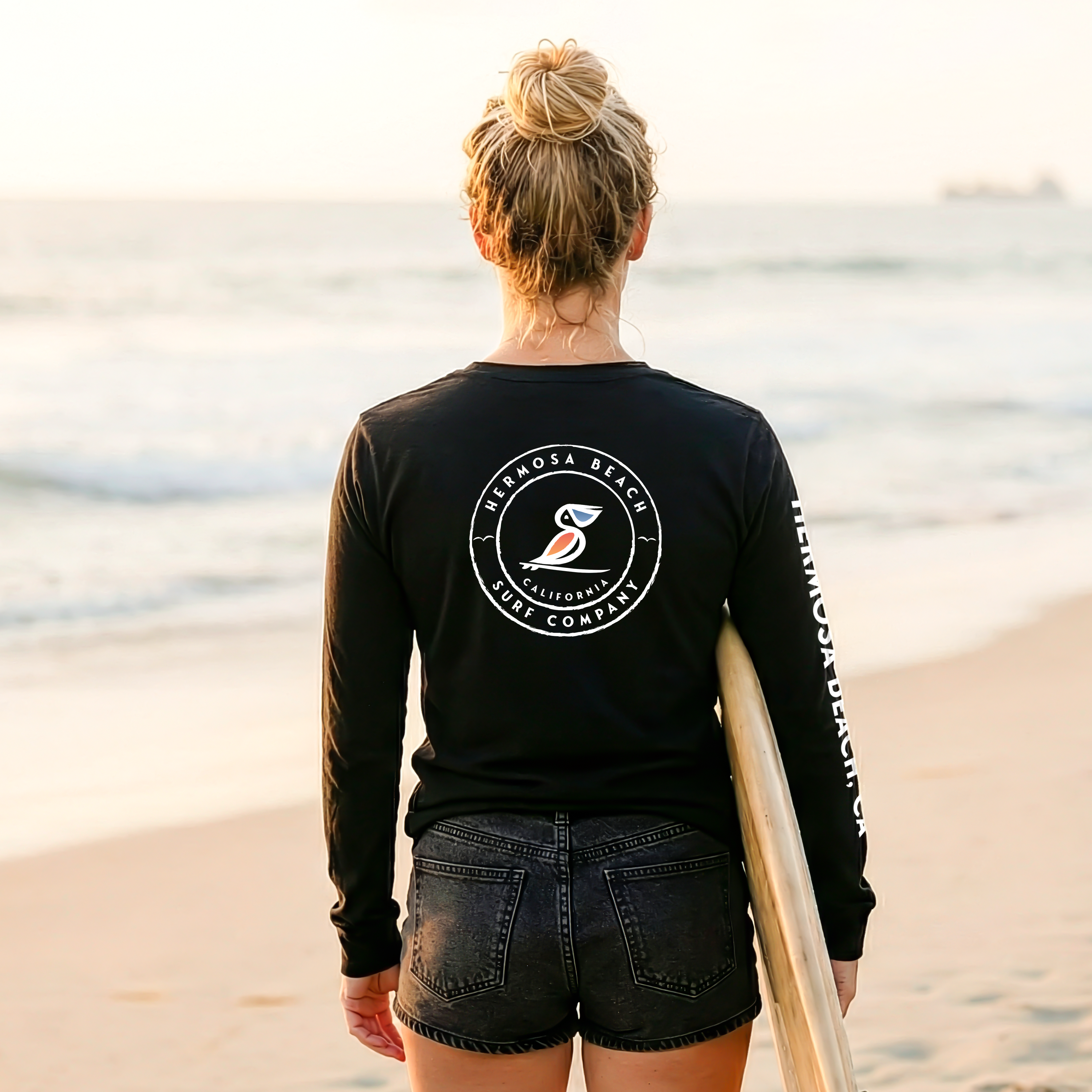 Person wearing a black long-sleeve shirt with a logo on the beach