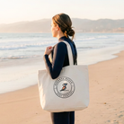 Person holding a tote bag with a logo on a beach