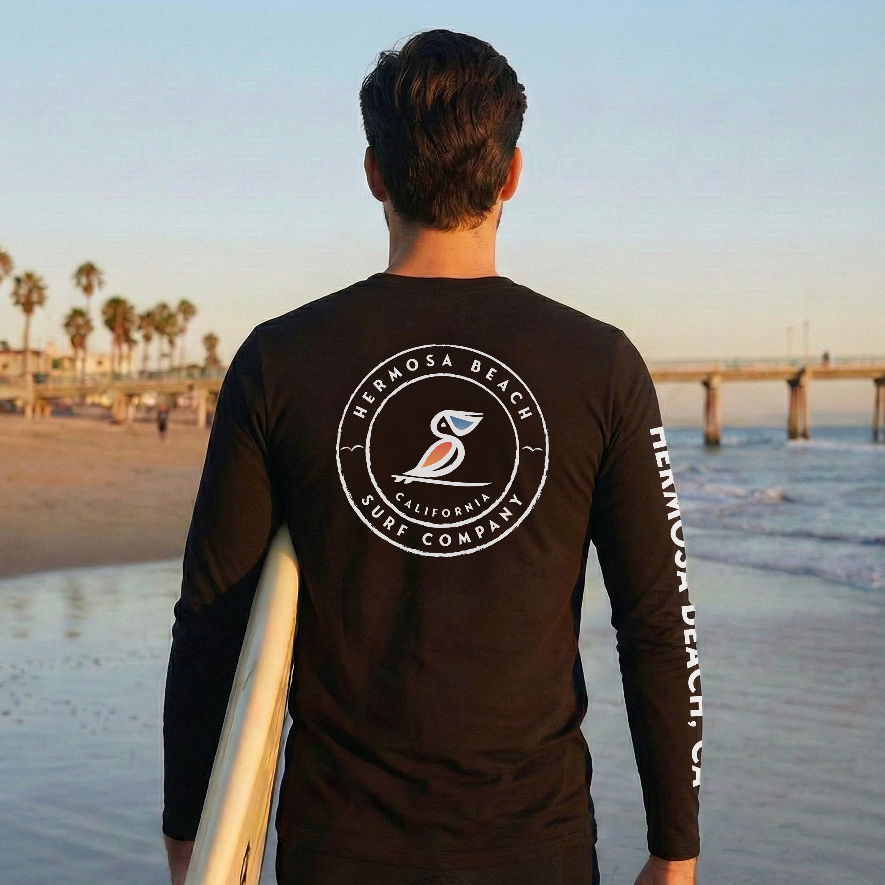 Person wearing a black long-sleeve shirt with a logo on the beach