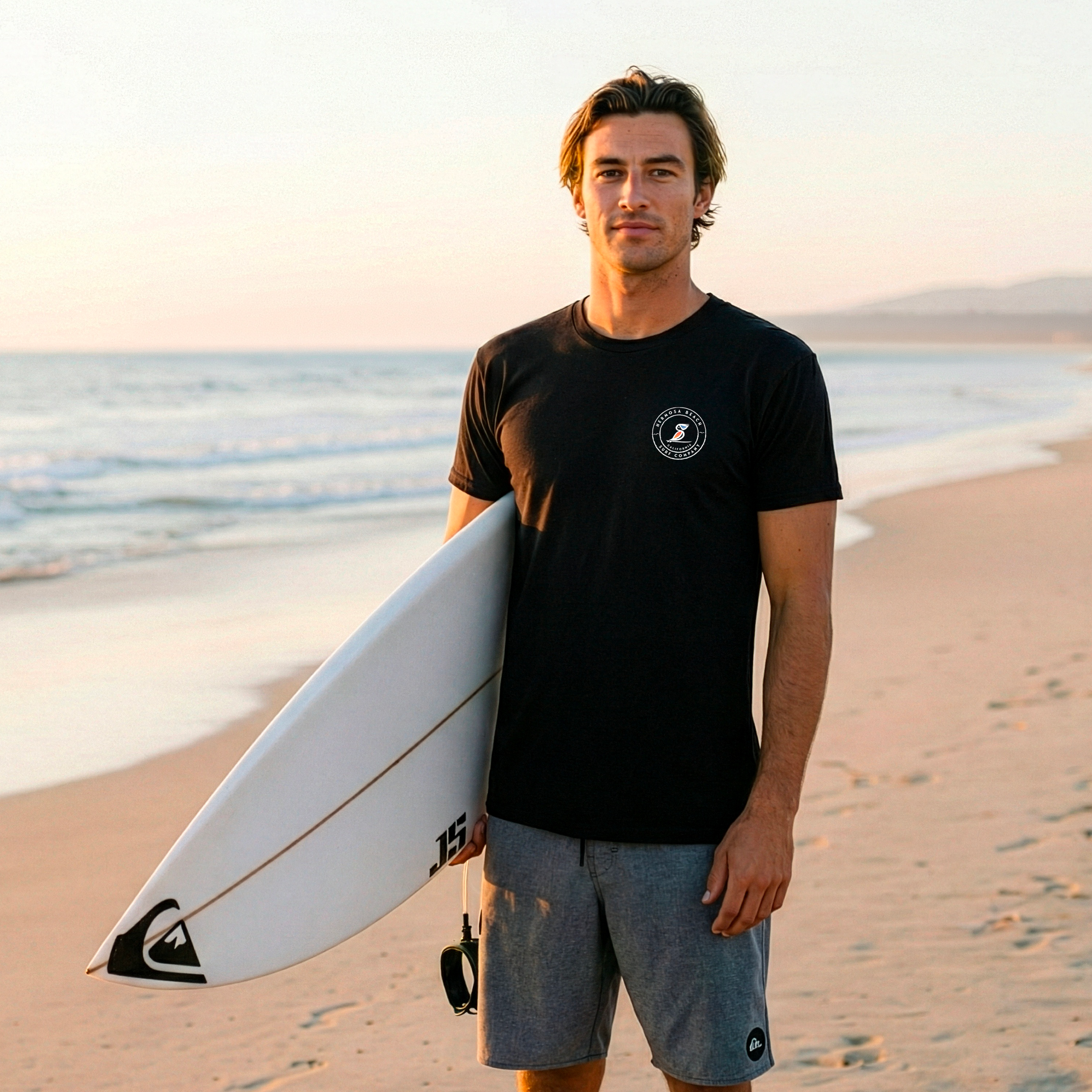Man holding a surfboard on a beach with ocean in the background