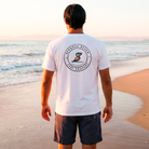 Man wearing a white t-shirt with a logo on the beach