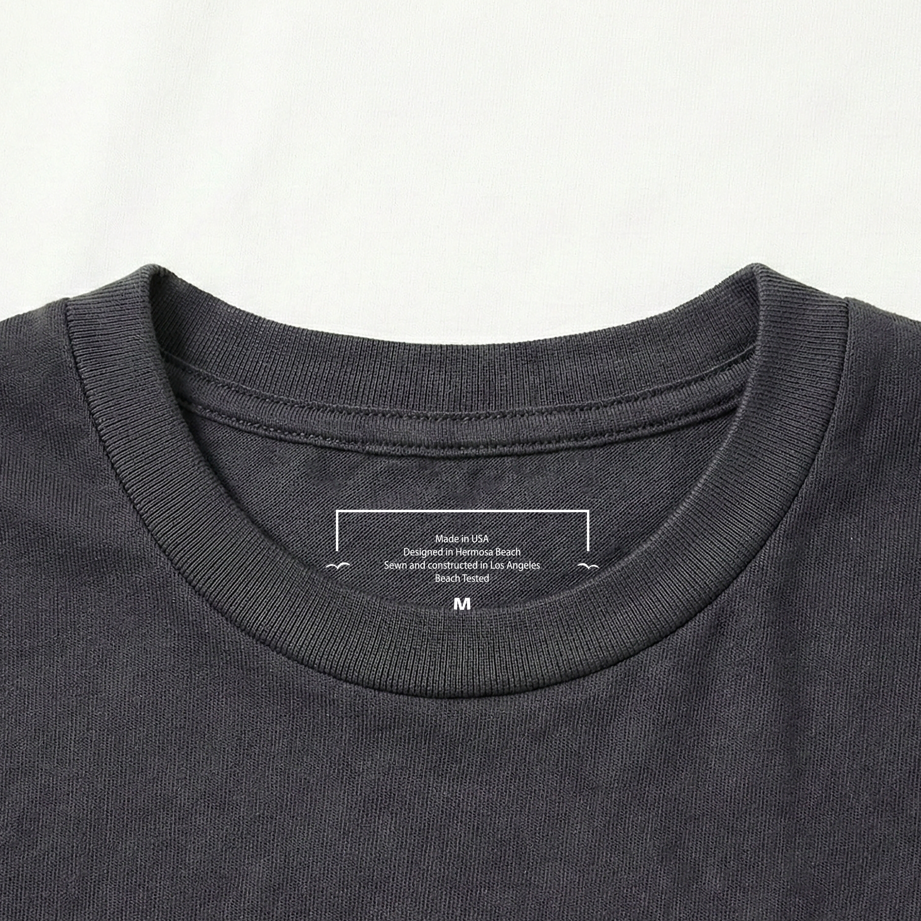 Close-up of a Vintage black t-shirt collar with branding text on a light gray background