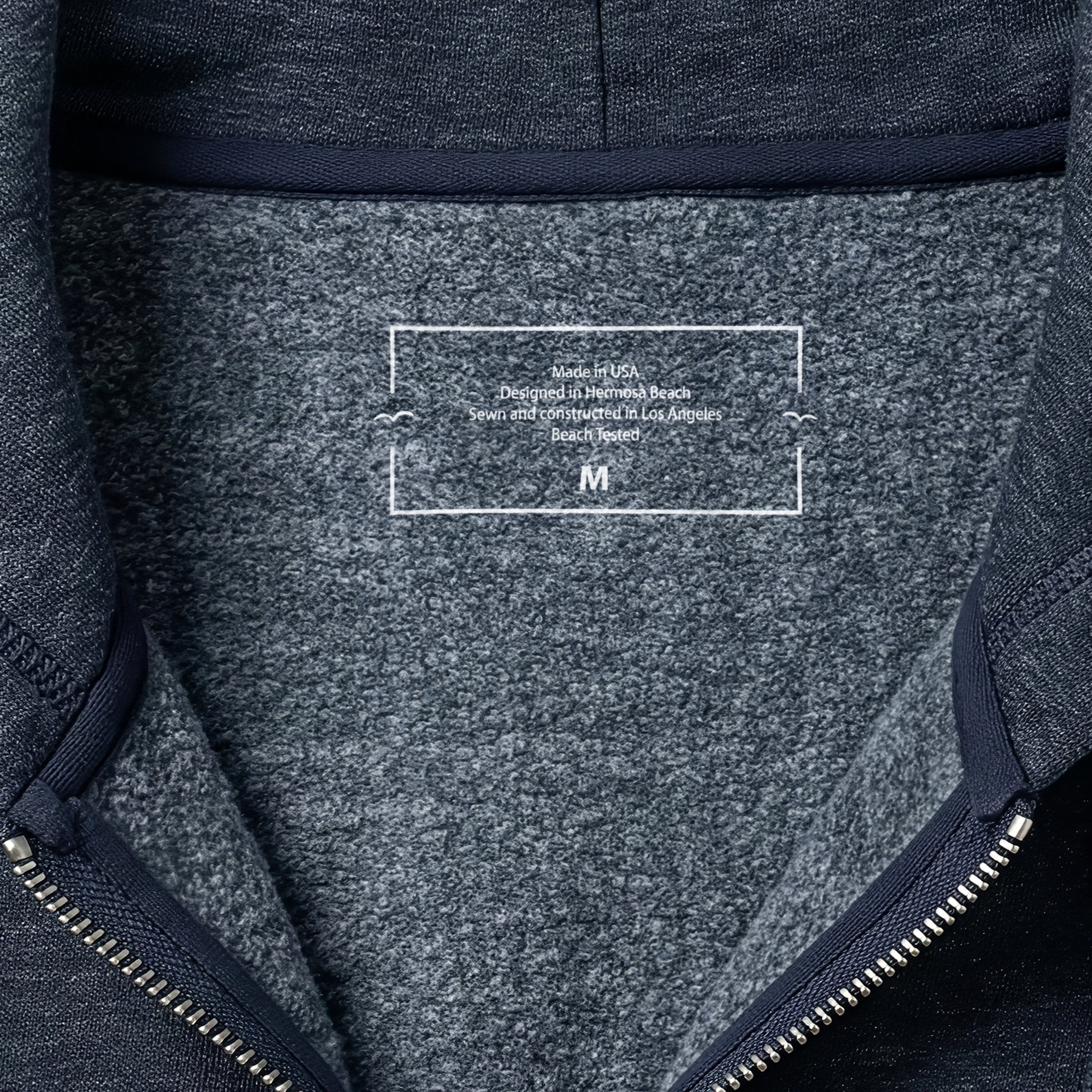 Close-up of a textured fabric label on a dark gray backpack with visible branding.