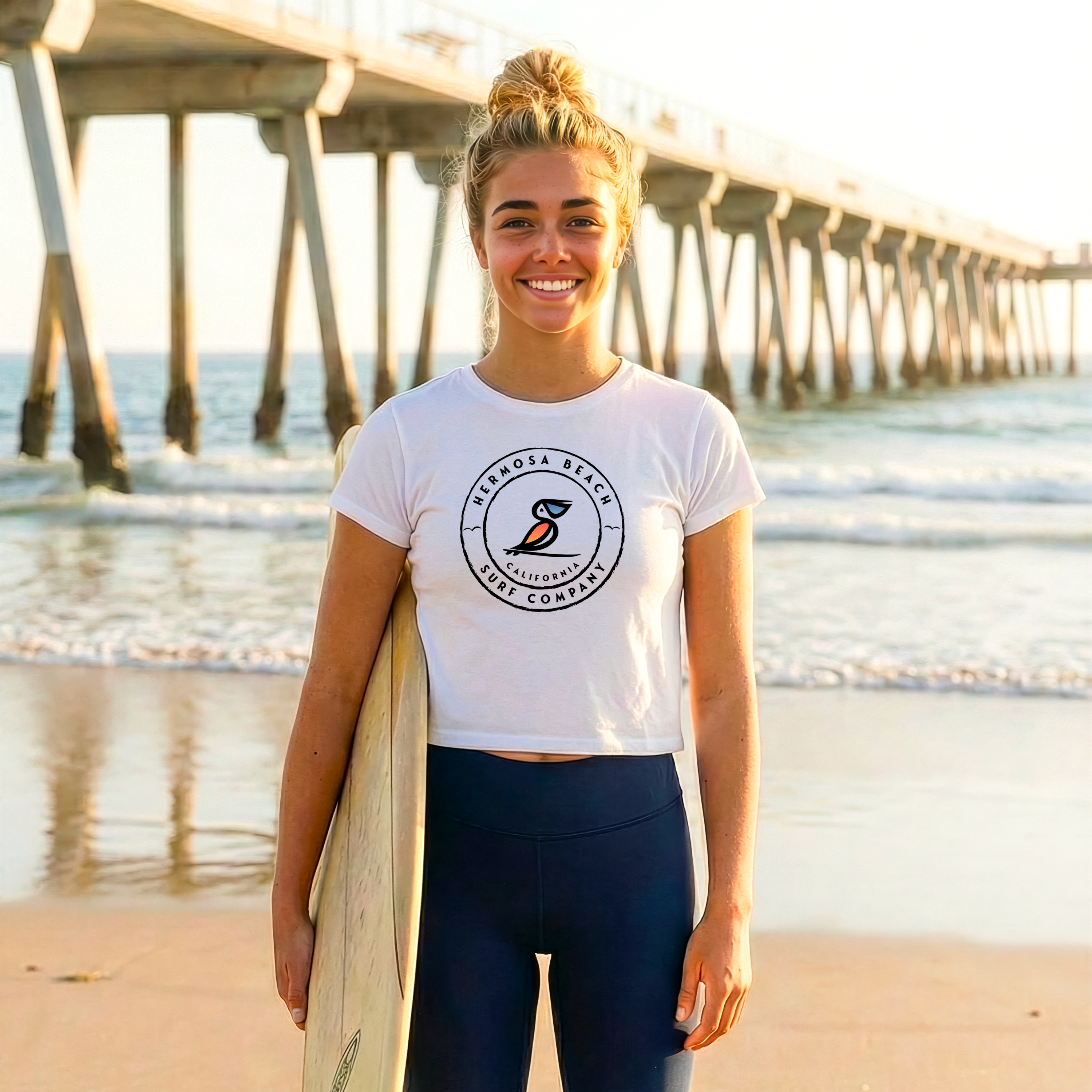 Woman holding a surfboard on a beach with a pier in the background