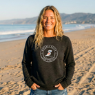 Woman wearing a Grey sweatshirt with a logo on a beach